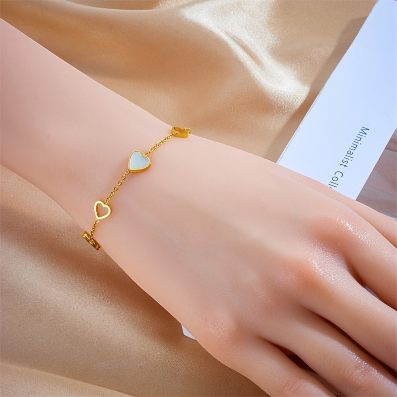 Brazalete Alma Cruz de acero inoxidable dorado con dijes de corazón esmaltados en blanco y oro, cadena ajustable.