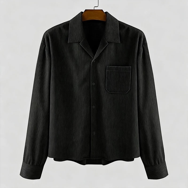 Camisa negra de pana de manga larga de Alma Cruz con cuello abierto y bolsillo en el pecho. Textura acanalada.