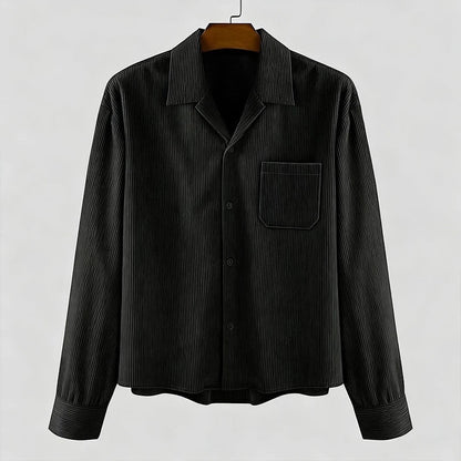 Camisa negra de pana de manga larga de Alma Cruz con cuello abierto y bolsillo en el pecho. Textura acanalada.