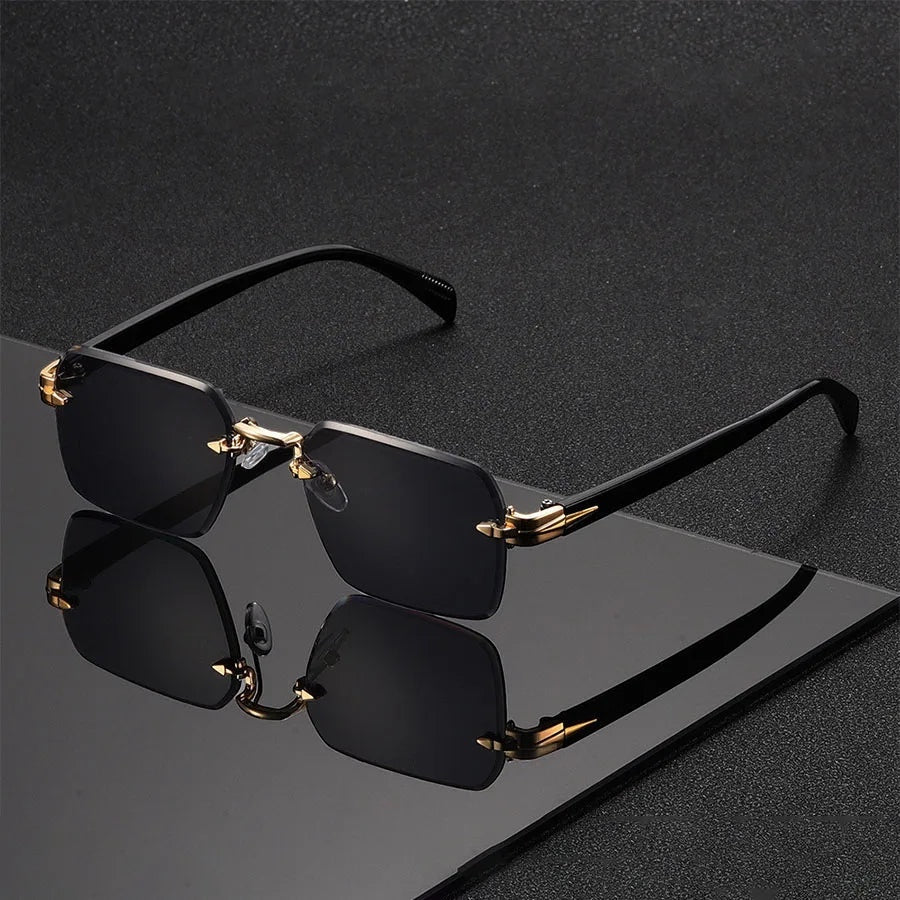Gafas de sol Alma Cruz Fausto sin montura, lentes degradadas negras, puente y detalles dorados, patillas negras.
