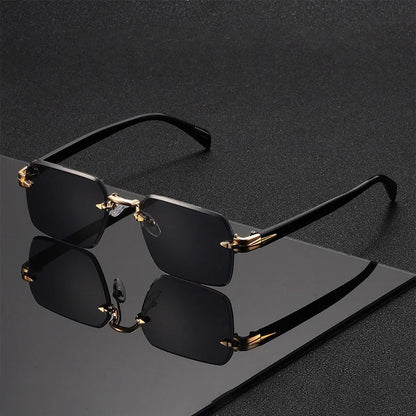 Gafas de sol Alma Cruz Fausto sin montura, lentes degradadas negras, puente y detalles dorados, patillas negras.