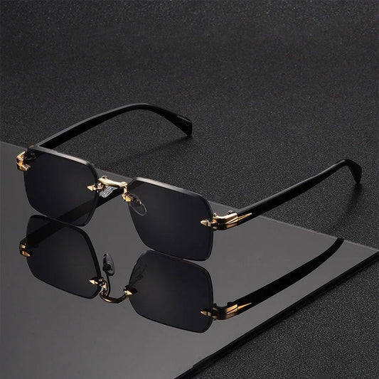 Gafas de sol Alma Cruz Fausto sin montura, lentes degradadas negras, puente y detalles dorados, patillas negras.