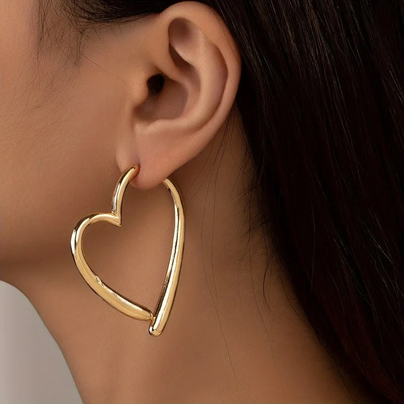Pendientes de aro dorados con forma de corazón entrelazado de Alma Cruz. Metal brillante.