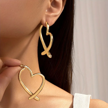 Pendientes de aro dorados de metal con diseño de corazón entrelazado de Alma Cruz. Elegantes y modernos.