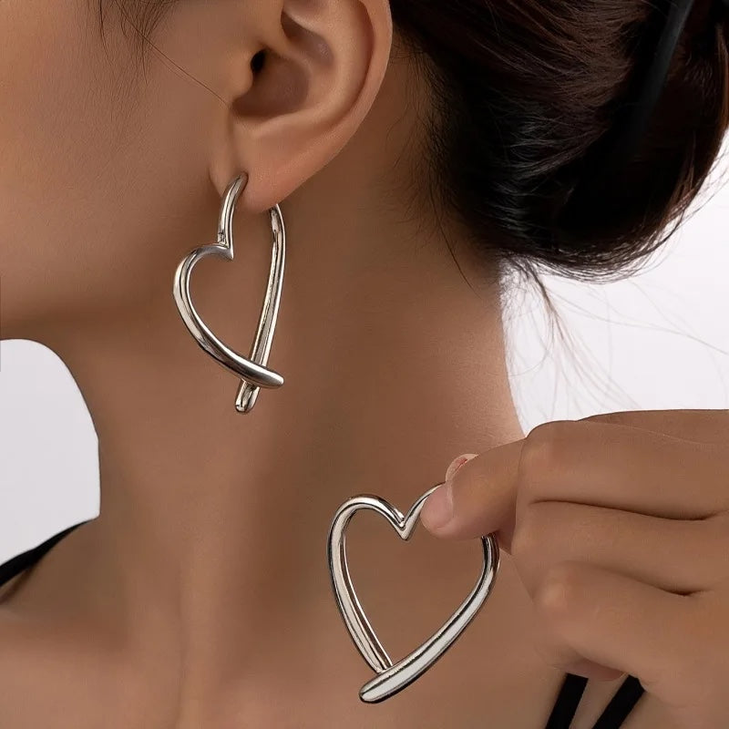 Pendientes de aro plateados de metal con diseño de corazón entrelazado de Alma Cruz. Elegantes y modernos.