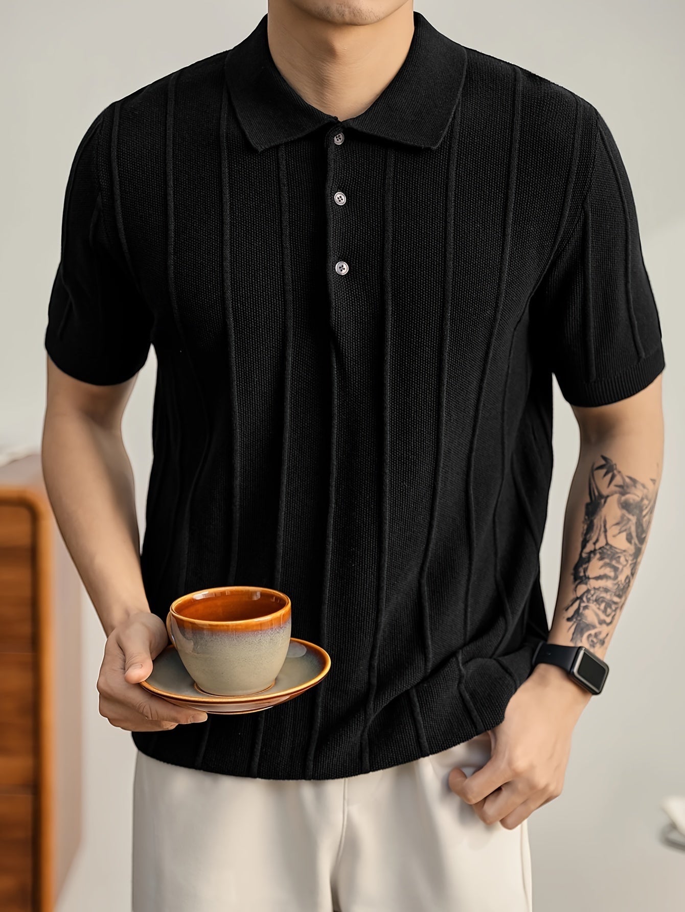 Polo negro de punto de algodón peinado de Alma Cruz con canalé vertical, cuello estructurado y tapeta abierta.