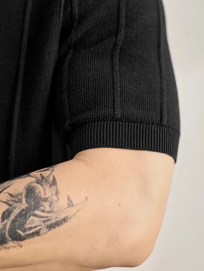 Alma Cruz polo negro de algodón peinado con canalé vertical texturizado y cuello estructurado.