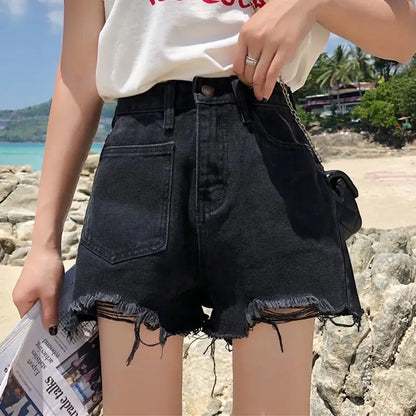Alma Cruz shorts vaqueros negros de talle alto con rotos y bajo deshilachado, estilo desgastado.