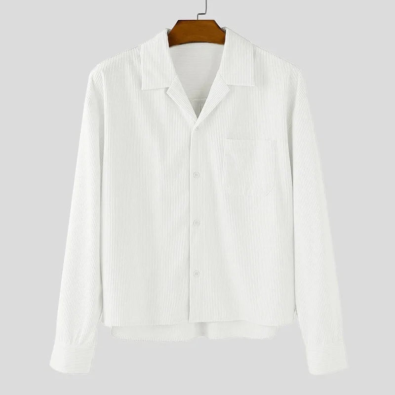 Sobrecamisa blanca de pana de Alma Cruz con cuello abierto, bolsillo en el pecho y cierre de botones. Textura acanalada.
