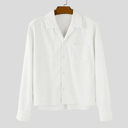 Sobrecamisa blanca de pana de Alma Cruz con cuello abierto, bolsillo en el pecho y cierre de botones. Textura acanalada.