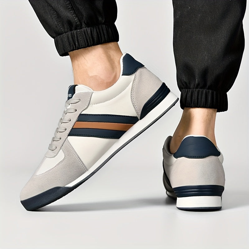 Zapatillas deportivas Alma Cruz de piel blanca y gris con rayas azul marino y marrón, suela acolchada.