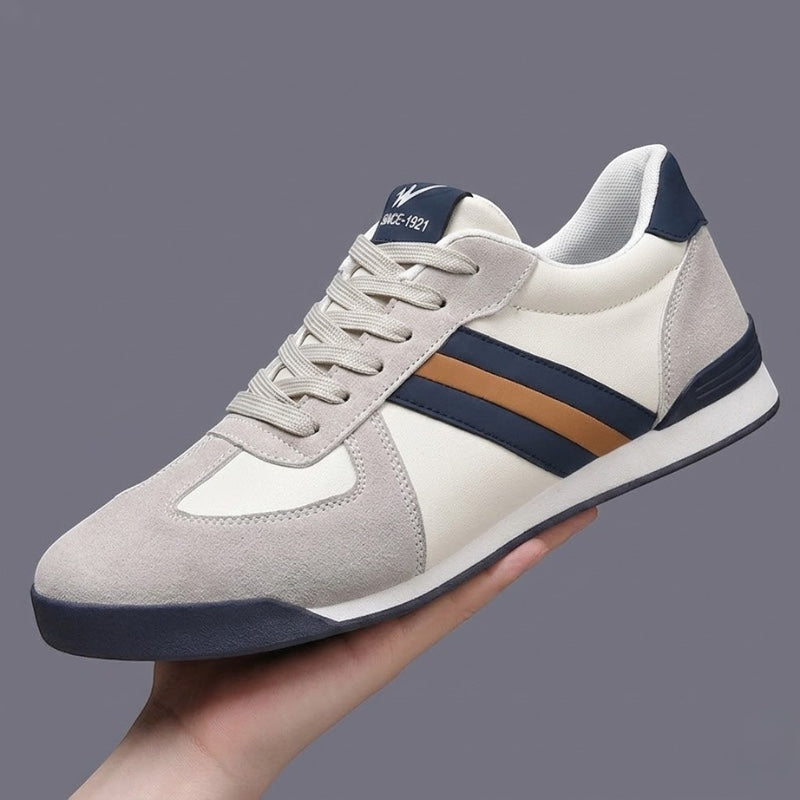 Zapatillas deportivas retro de piel auténtica Alma Cruz en blanco y gris con rayas azul marino y marrón, suela acolchada.