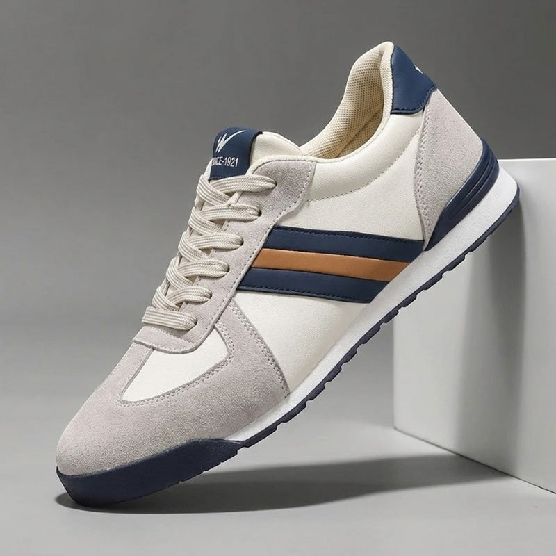 Zapatillas deportivas Alma Cruz de piel en blanco roto, gris y azul marino con detalles marrones. Diseño retro.