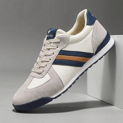 Zapatillas deportivas Alma Cruz de piel en blanco roto, gris y azul marino con detalles marrones. Diseño retro.